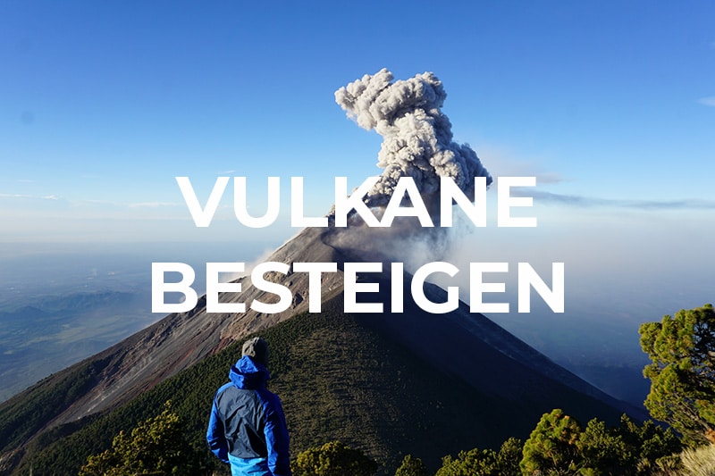 Mann steht vor qualmendem Vulkan
