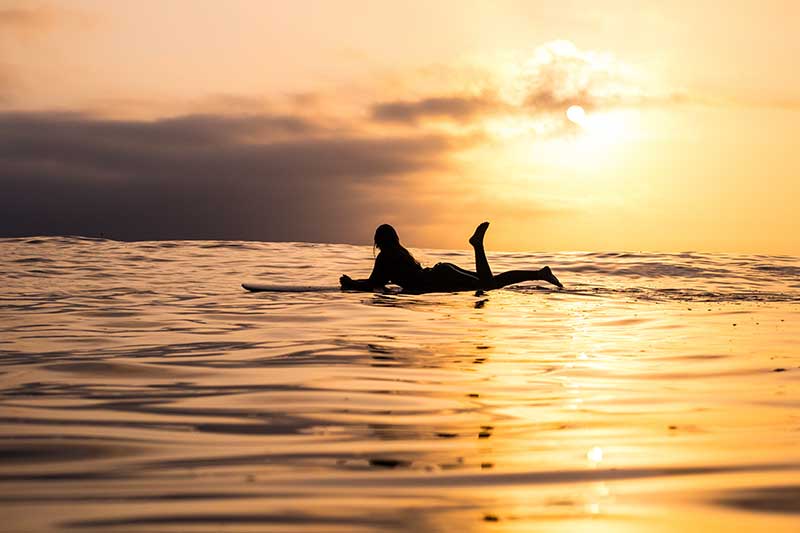 Surferin liegt auf Surfbrett im Meer in Costa Rica